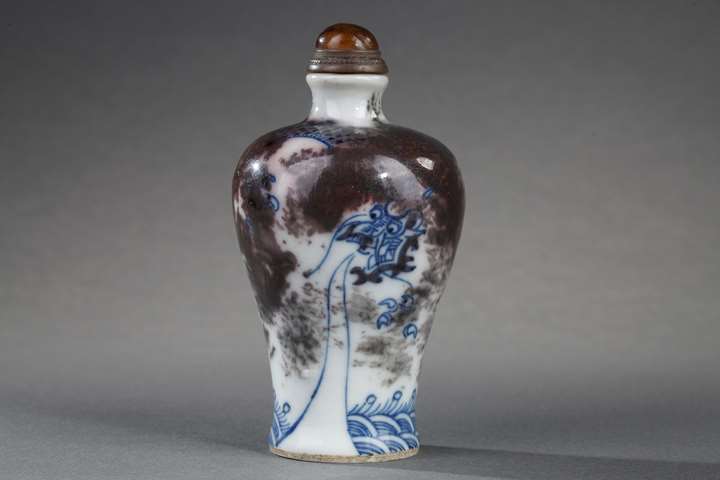 Snuff bottle porcelain enamelled in underglaze blue and copper red decorated with a Dragon in a clouds